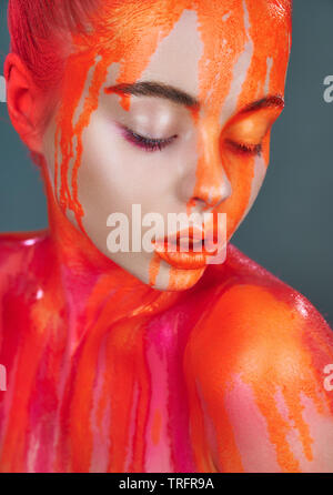 Modello di donna con il trucco e la perdita di colore arancione vernice al neon. Glitter vivid trucco. Alta Moda modello Foto Stock
