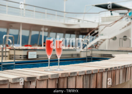 Due bicchieri di champagne rosa vicino a una piscina su una vacanza in crociera. Foto Stock