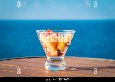 Una sana insalata di frutta in vaso di vetro sulla vacanza di estate. Sfondo oceano. Foto Stock