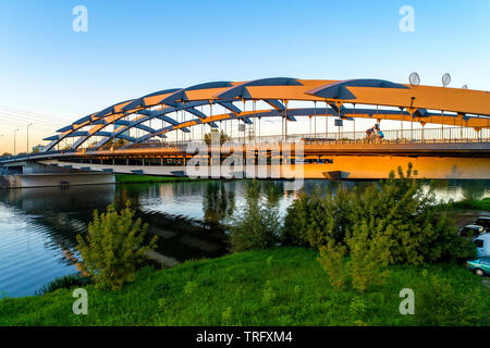 Sospensione ponte Kotlarski oltre il fiume Vistola a Cracovia, Polonia, nella luce del tramonto con un irriconoscibile ciclisti. Foto Stock