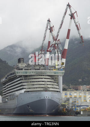 Genova Italia 19 Maggio 2019: nuova nave da crociera scarlet lady in costruzione attraccata ad una banchina di un cantiere con gru di grandi dimensioni Foto Stock