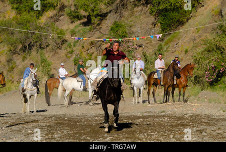 Tradizionale nastro horse racing al Benamargosa Romeria. Equitazione la concorrenza si svolge lungo il letto del fiume secco come parte del festival Foto Stock