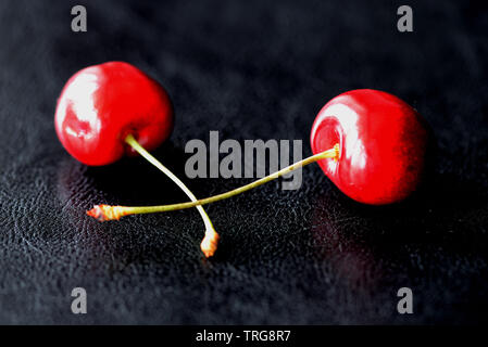 Due bacche mature di ciliegio dolce su uno sfondo scuro vicino fino Foto Stock