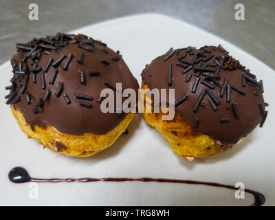 Profiterol ricoperti di cioccolato e di confetti Foto Stock