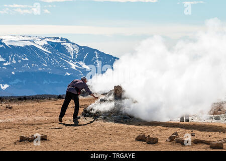 Un turista imprudentemente prove il calore di una fumarola nel altamente attivo area geotermica a Námafjall (Hverir), nei pressi del lago Mývatn nel nord-est dell'Islanda Foto Stock