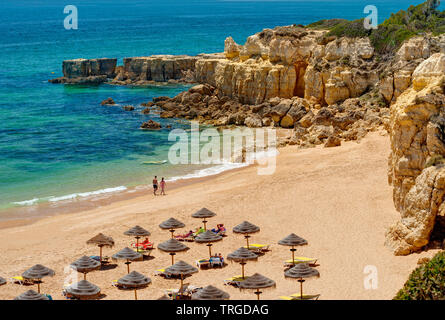 Una grotta nei pressi di Albufeira con un paio di camminare sulla spiaggia, Algarve, PORTOGALLO Foto Stock