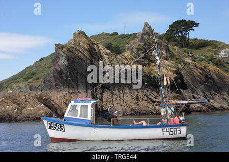 Il porto esterno di Polperro a bassa marea: un pescatore si rilassa nella sua barca "Stella del Nord' Foto Stock