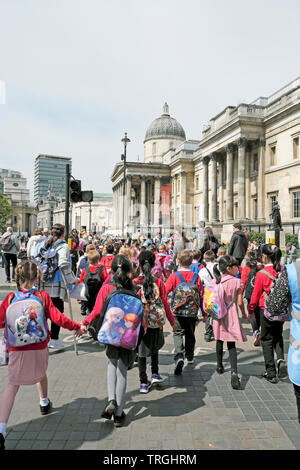 Un gruppo di studenti della scuola primaria gli alunni e gli insegnanti a piedi lungo la strada per visitare il National Gallery di Londra Inghilterra REGNO UNITO KATHY DEWITT Foto Stock