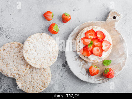 Organico sano torte di riso con ricotta e fragole fresche sulla pietra di luce sullo sfondo della cucina. Foto Stock