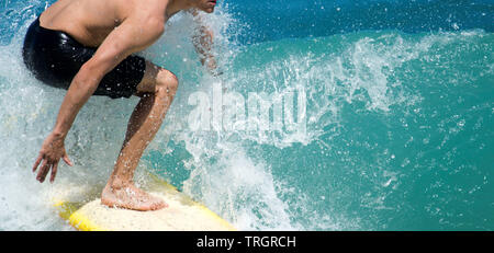 Un surfista naviga il suo modo mentre in sella a una bella onda nell'oceano Foto Stock