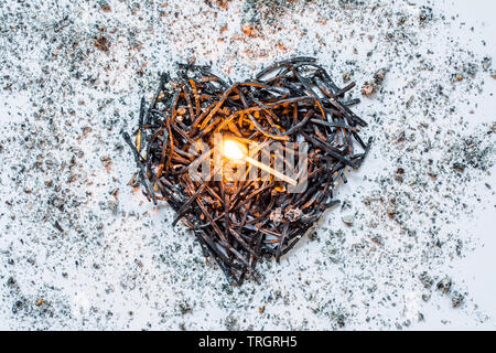 Il simbolo del cuore di fatto di bruciato-verso il basso corrisponde da vicino con un fiammifero che brucia nel centro e la cenere intorno a. Il concetto di complessità delle relazioni di amore Foto Stock