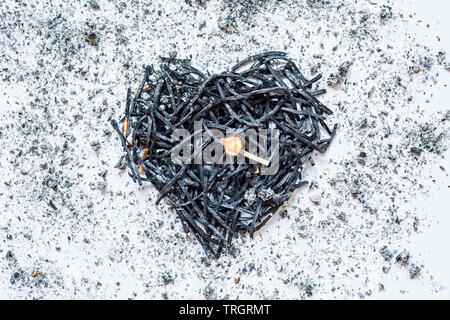 Il simbolo del cuore di fatto di bruciato-verso il basso corrisponde da vicino con un fiammifero che brucia nel centro e la cenere intorno a. Il concetto di complessità delle relazioni di amore Foto Stock