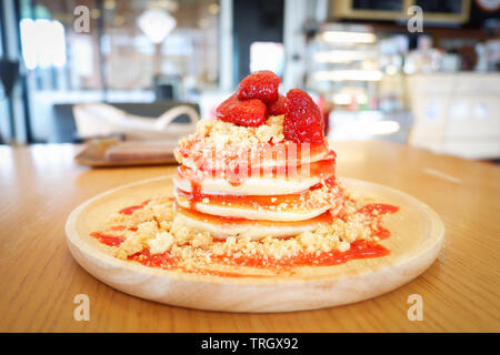 Frittelle di frutta fragola e salsa su sfondo di legno nella torta di caffè e coffee shop Foto Stock