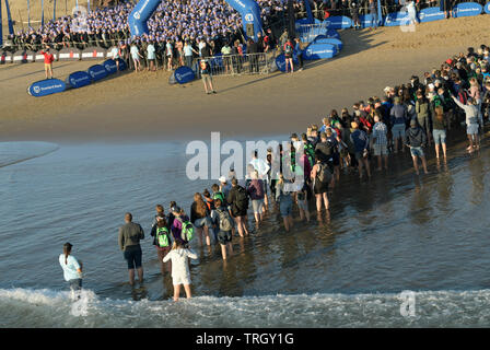 Durban, KwaZulu-Natal, in Sudafrica, la folla di persone in piedi in acqua guardando gli atleti partono nuotare gamba di triathlon, 2019, Ironman 70,3, sport Foto Stock