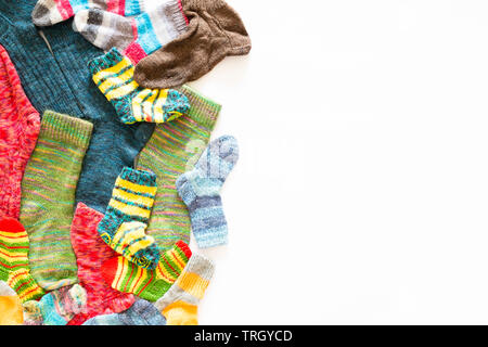 Vista dall'alto di un assortimento di coloratissimi calzini di lana di varie dimensioni su sfondo bianco Foto Stock