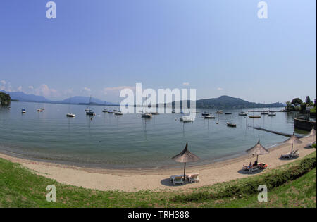Il Lago Maggiore spiaggia in una baia con barche a vela ormeggiata. Italia Foto Stock