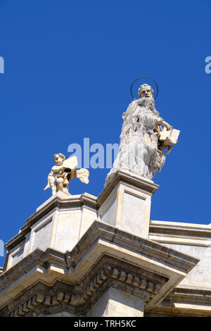 La statua di un santo e un cherubino sulla cima del duomo di Catania, Sicilia, Italia Foto Stock