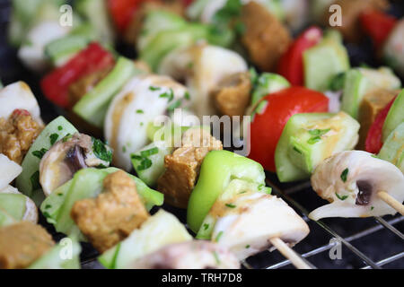 Gli spiedini di verdure alla griglia con seitan, funghi, zucchine, pomodori e peperoni Foto Stock