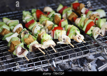 Gli spiedini di verdure alla griglia con seitan, funghi, zucchine, pomodori e peperoni Foto Stock
