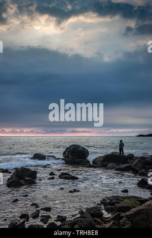 L'uomo guarda il mare orizzonte da permanente sulla roccia al tramonto punto kanyakumari tamilnadu india. Foto Stock