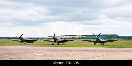 Tre diverse varianti di Supermarine Spitfire, due Mk.Ia e un Mk.IXb, schierate all'aeroporto di Duxford IWM Foto Stock