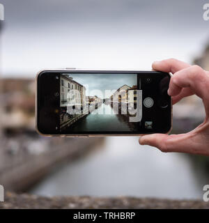 Milano, Italia - 19 Aprile 2019: turistica prendendo foto del Naviglio Grande in Milano Italia con un telefono cellulare. Concetto di viaggio. Vista sulla piazza Foto Stock