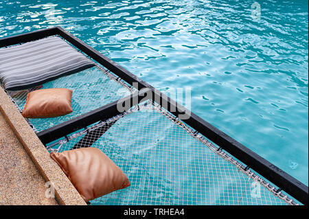 Maglia relax sedile con cuscini sporgere sulla piscina Foto Stock