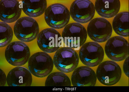In vetro scuro di sfere su sfondo giallo vista ravvicinata Foto Stock