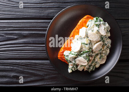 Cotto Fiorentino con salmone cremosa salsa di vino, condito con arrosti di spinaci e funghi closeup su una piastra sul tavolo. Parte superiore orizzontale vista dal Foto Stock