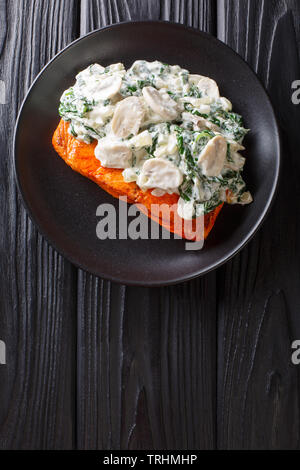 Cotto Fiorentino con salmone cremosa salsa di vino, condito con arrosti di spinaci e funghi closeup su una piastra sul tavolo. Verticale in alto vista da ab Foto Stock