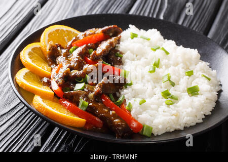 Stir-fried sticky carni bovine con il peperone in semi di soia Salsa di arancia servito con riso close-up su una piastra sul tavolo orizzontale. Foto Stock