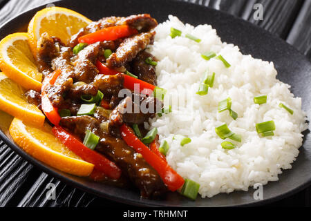 Asian rosolare la carne bovina con il peperone in semi di soia Salsa di arancia servito con riso close-up su una piastra sul tavolo orizzontale. Foto Stock