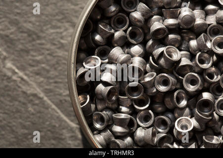 Una lattina di piombo .22 calibro airgun pellets al buio su un sfondo di pietra che può essere utilizzato in entrambi i fucili ad aria compressa o pistole ad aria compressa. Inghilterra REGNO UNITO GB Foto Stock