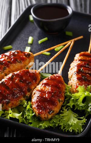 Giapponese polpette di pollo che sono infilzato e tipicamente alla griglia su carbone servita nel ristorante yakitori closeup su di una piastra verticale. Foto Stock