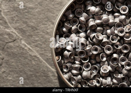 Una lattina di piombo .22 calibro airgun pellets al buio su un sfondo di pietra che può essere utilizzato in entrambi i fucili ad aria compressa o pistole ad aria compressa. Inghilterra REGNO UNITO GB Foto Stock