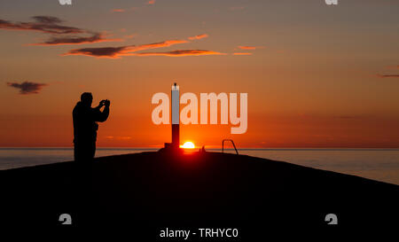 Aberystwyth, Ceredigion, Wales, Regno Unito. Il 6 giugno, 2019. Regno Unito: Meteo a profilarsi l uomo si prende una foto mentre si sta in piedi sul molo di cemento al tramonto su questa tranquilla serata a Aberystwyth. Credito: Ian Jones/Alamy Live News Foto Stock