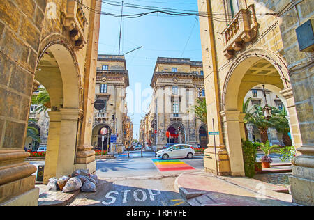 FLORIANA, Malta - 19 giugno 2018: la vista su vasta St Anne avenue attraverso le strette strade di pietra, foderato con edifici storici e gallerie commerciali, su Foto Stock