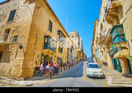 La Valletta, Malta - 17 giugno 2018: la lunga ascesa nella Repubblica street, foderato con vecchi edifici in pietra, negozi, caffetterie e ristoranti familiari, sul ju Foto Stock