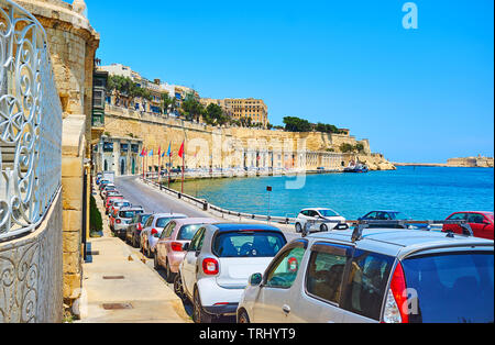 A piedi lungo la barriera Wharf con una vista sul Grand Harbour e alti bastioni di Santa Barbara bastione della fortificazione di La Valletta, Malta. Foto Stock