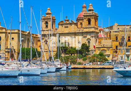 La facciata della ornati in chiesa di San Lorenzo da Vittoriosa marina con yacht ancorati sul primo piano, Malta. Foto Stock