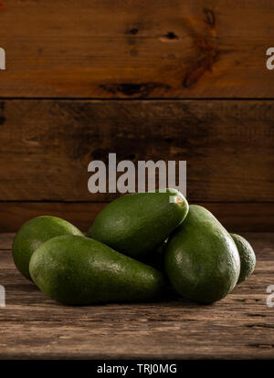 Pila di con la buccia verde brillante avocadi su legno tavolo rustico Foto Stock