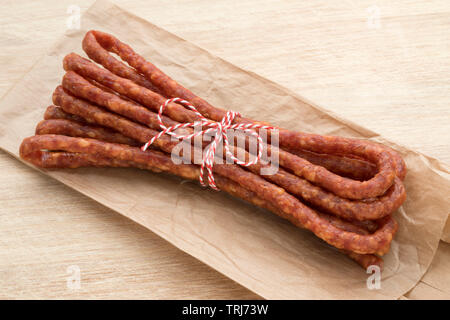 Unico sottile polacco Kabanosy salsiccia close up giacente su un sacco di carta Foto Stock