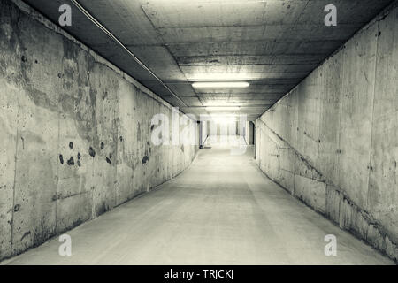 Vuoto, tunnel come rampa di discesa di un parcheggio auto sotterraneo. Immagine in bianco e nero Foto Stock