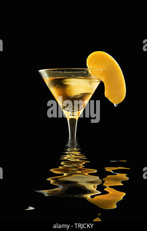 Appletini fresca in un sudato bicchiere da cocktail con ghiaccio fondente, guarnita con apple slice con appeso waterdrop, allagata e riflessa su acqua, contro Foto Stock