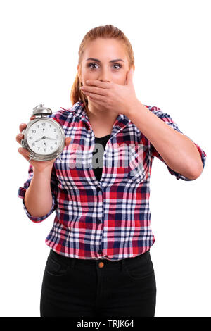 Ritratto di una giovane bella donna vestita di plaid shirt tenendo un vecchio orologio sveglia, scioccato e sorpreso di vedere che cosa è il tempo. Isolato o Foto Stock