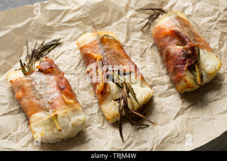 Tre cuocere i filetti di merluzzo giallo, Pollachius pollachius, che sono state conservate in succo di limone e aglio schiacciato prima di essere avvolto in prosciutto di Parma w Foto Stock