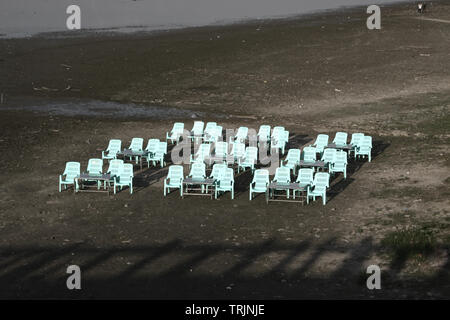 Svuotare le sedie in plastica con tabelle su un vuoto spiaggia depressivo