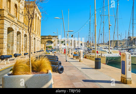 Il vecchio Xatt Il-Forn promenade è decorata con vecchi cannoni, in piedi lungo la parete del museo marittimo di Birgu, Malta. Foto Stock