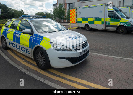 Una macchina della polizia e un'emergenza ambulanza parcheggiata fuori l'incidente e unità di emergenza di University Hospital, Wishaw, North Lanarkshire, Scotland, Regno Unito Foto Stock