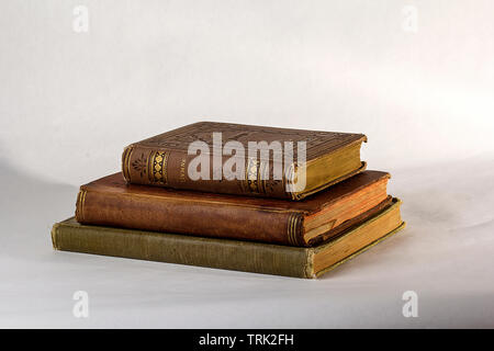 Pila di tre libri antichi su uno sfondo bianco. Foto Stock